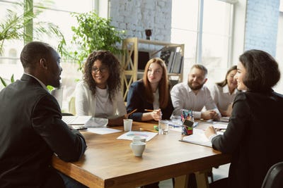 A group of young diverse professionals sitting around a table having a meeting